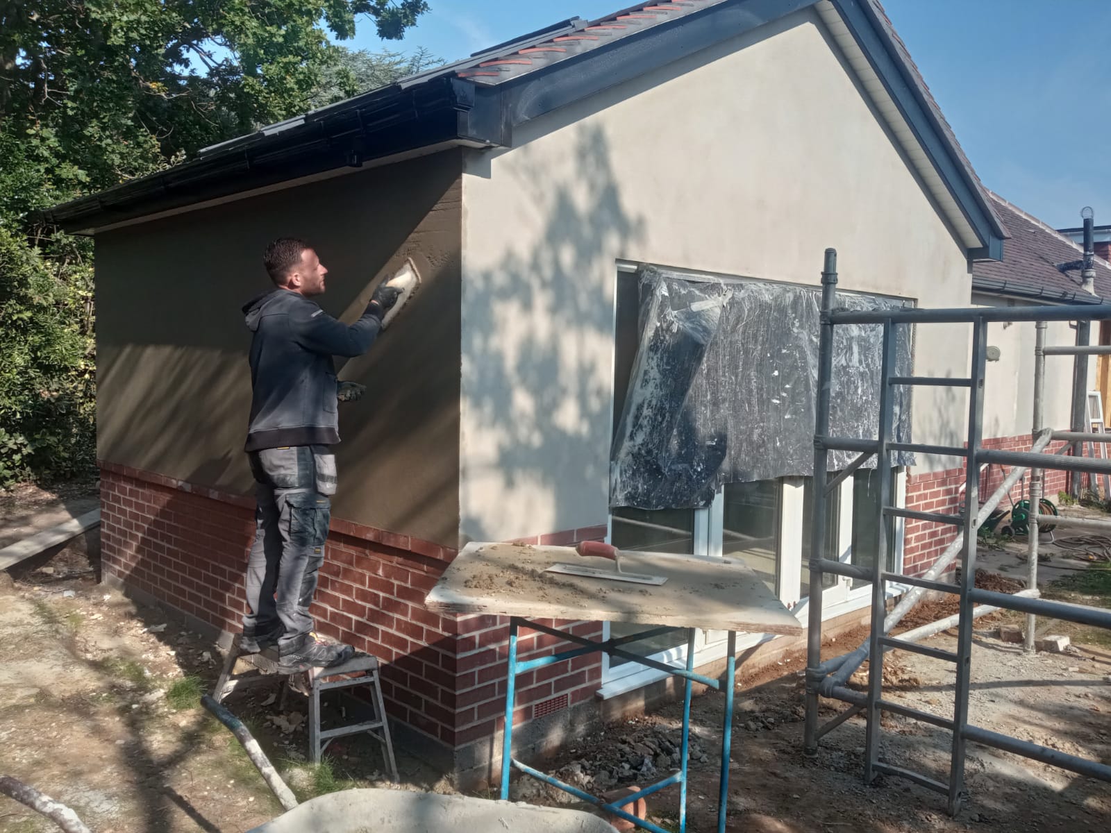 Professional renderer applying modern external wall render to a house in Bournemouth during exterior renovation work